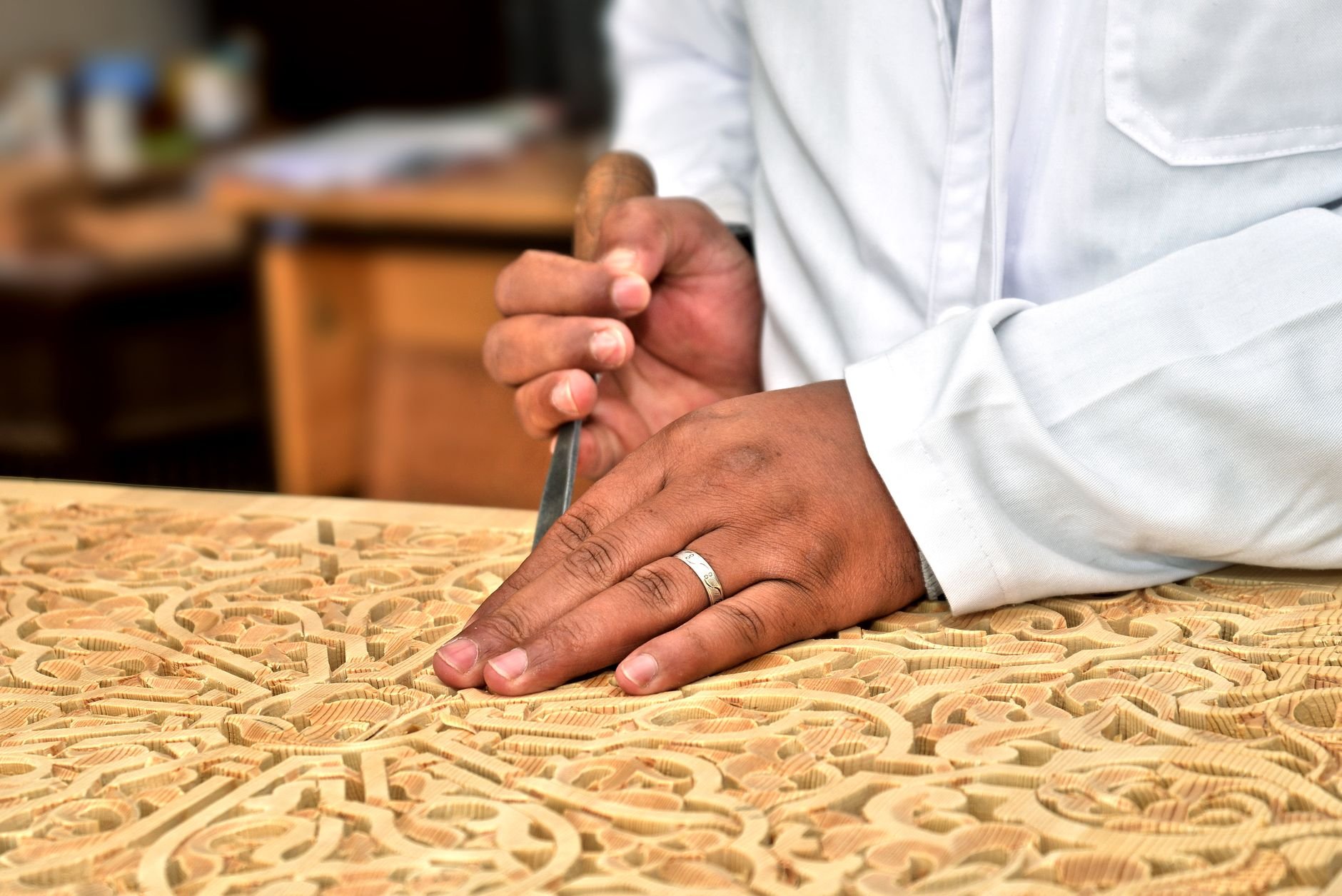Close-up of an artisan's hands skillfully carving wood in a traditional workshop.